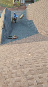 A man working on a roof under the bright daylight, focused on his task.